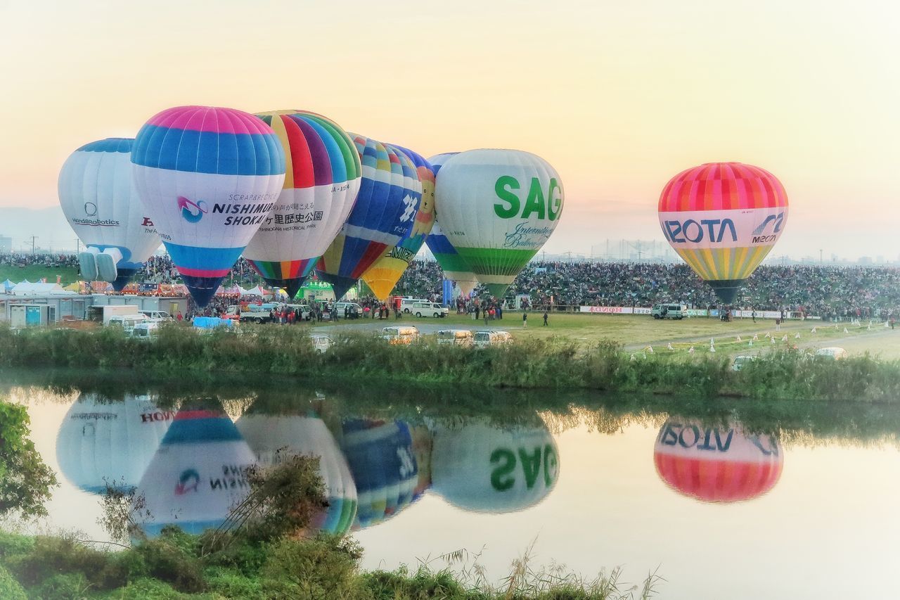 MULTI COLORED HOT AIR BALLOON IN LAKE AGAINST SKY
