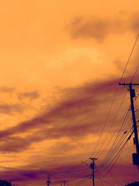 Low angle view of silhouette electricity pylon against dramatic sky