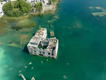 High angle view of people swimming by ruined building in sea