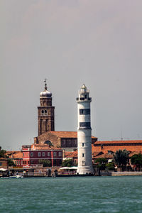 Lighthouse by sea against sky