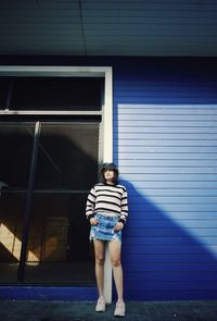 Full length portrait of girl standing against building