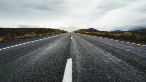 Empty road against cloudy sky