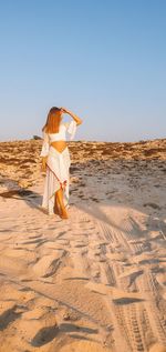 Rear view of woman on beach against clear sky