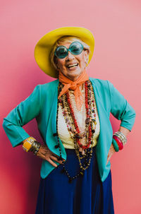 Portrait of smiling woman standing against pink background