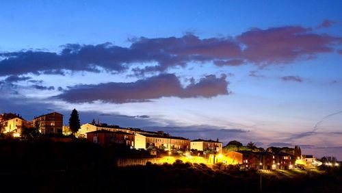 Illuminated cityscape against sky at sunset