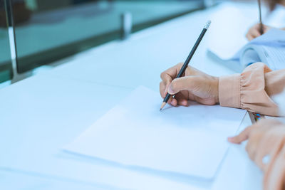 Midsection of person holding paper on table