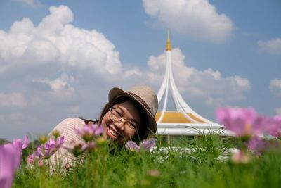 Rear view of woman with pink flowers against sky