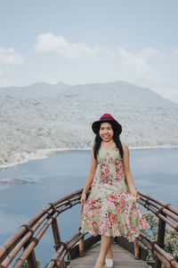 Portrait of young woman standing against sea