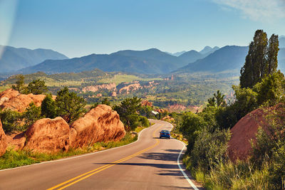 Road amidst trees and mountains against sky