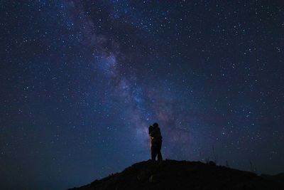Rear view of man standing against sky at night