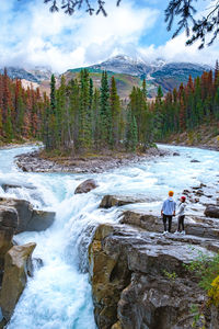 Rear view of men fishing in mountains against sky