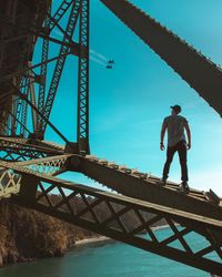 Man standing on bridge against sky