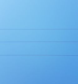 Low angle view of birds flying against clear blue sky