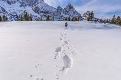 Man leaving foot prints in the snow against mountain landscape