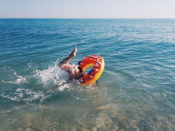 Low section of young woman with inflatable ring swimming in sea