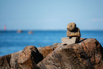 Stack of rocks by sea against blue sky