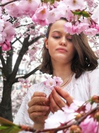 Portrait of beautiful woman holding pink cherry blossom