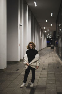 Portrait of young woman standing in city during winter at night