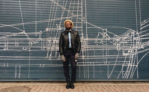 Portrait of a young man standing against brick wall