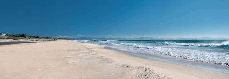 Scenic view of beach against clear blue sky