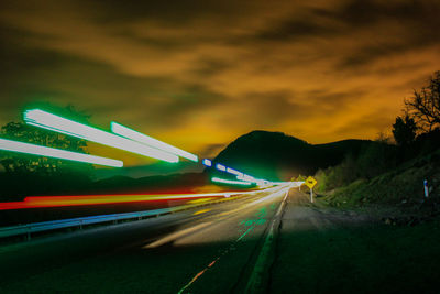 Light trails on road against sky at night