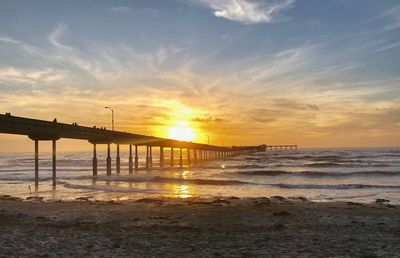 Bridge over sea against sky during sunset