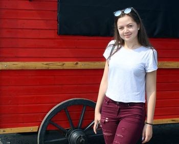 Portrait of smiling girl standing against red wall