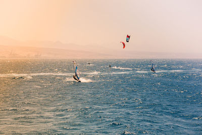 People kiteboarding in sea against sky