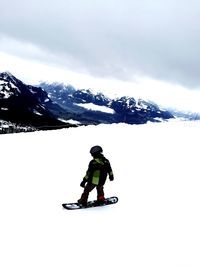 Woman jumping on snow covered mountain