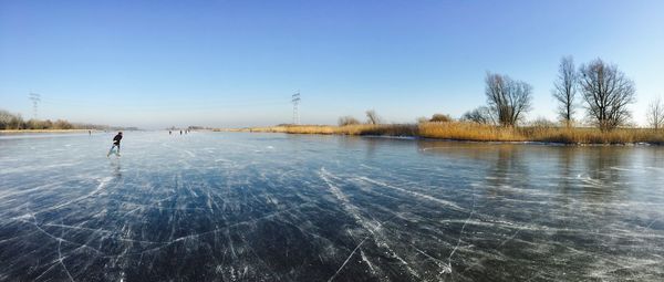 Scenic view of frozen lake against clear blue sky