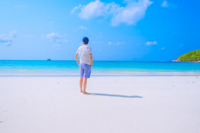 Rear view of man standing on beach against sky