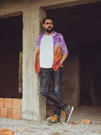 Portrait of young man standing against brick wall