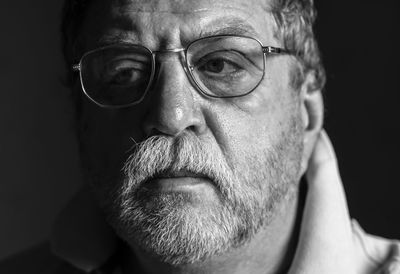 Close-up of thoughtful man with eyeglasses against black background