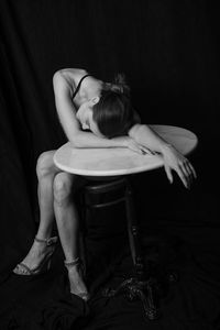 Woman lying on table while sitting against curtain