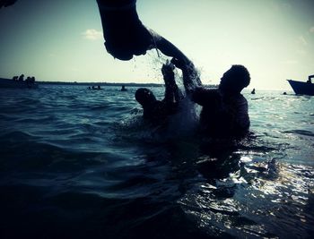 Man and woman playing in sea against sky