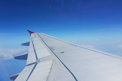 Cropped airplane wing against blue sky