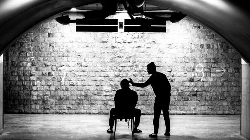 Silhouette people standing against brick wall