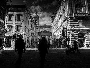 People walking in city against sky