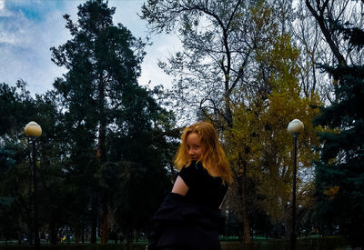 Portrait of woman standing against trees