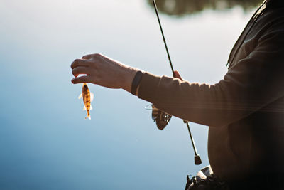 Fisherman with spinning rod and fish perch on river background. angler man with fishing spinning or