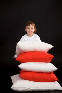 Portrait of happy boy standing against black background