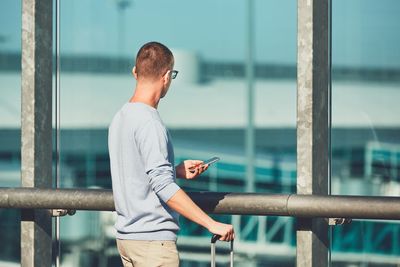 Close-up of man using mobile phone at railing