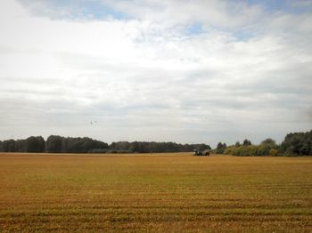 Scenic view of field against cloudy sky