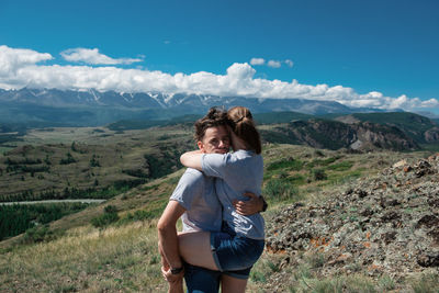 Young woman with arms raised on mountain against sky