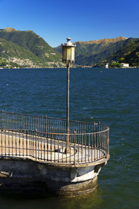 Electric lamp on pier at lake como against mountains