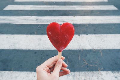 Close-up of cropped hand holding heart shaped ice cream