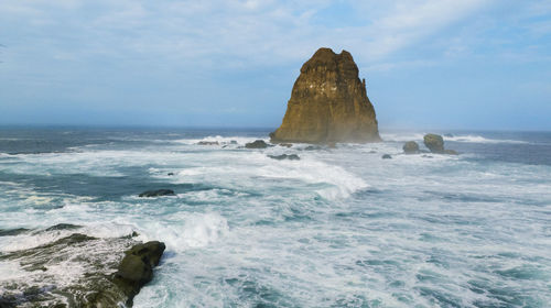 Rock formation in sea against sky