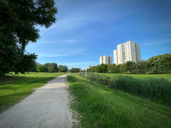 Road amidst field against sky in city