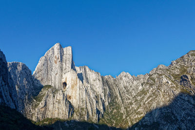 Low angle view of mountain against clear blue sky