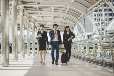 Full length of coworkers walking in office corridor